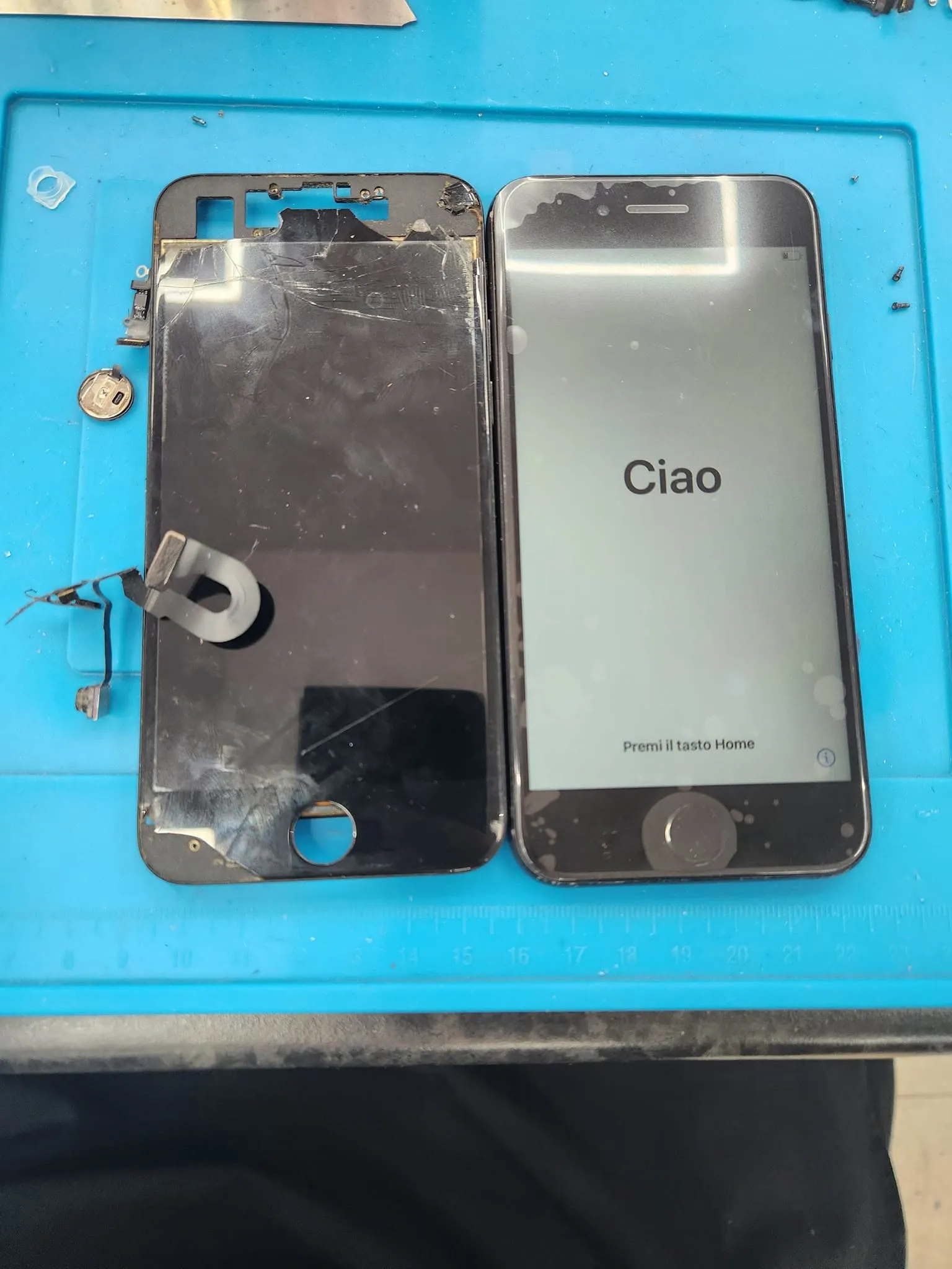 A damaged iPhone 8 screen assembly beside the phone with its new screen showing the setup screen.